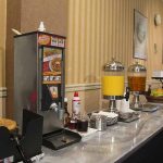 breakfast buffet set up with waffle machine and juice stations